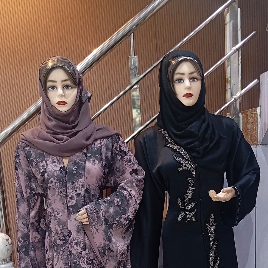 Two mannequins in a floral abaya and a black beaded abaya with hijabs